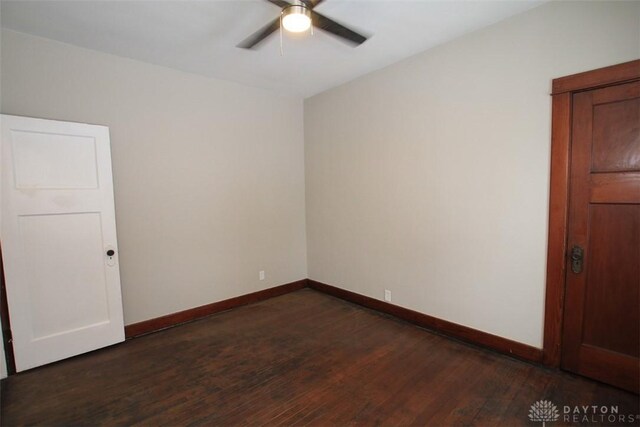 spare room featuring dark wood-style floors, a ceiling fan, and baseboards