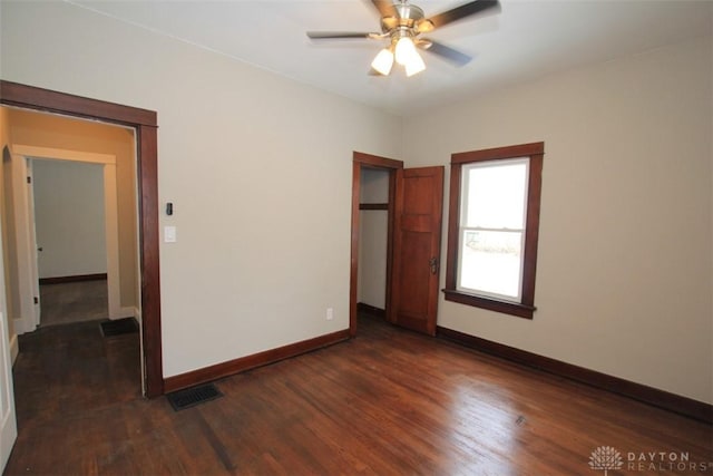 unfurnished bedroom with dark wood-style flooring, a closet, visible vents, ceiling fan, and baseboards