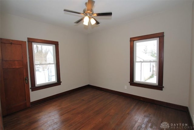 unfurnished room with dark wood-style flooring, plenty of natural light, a ceiling fan, and baseboards