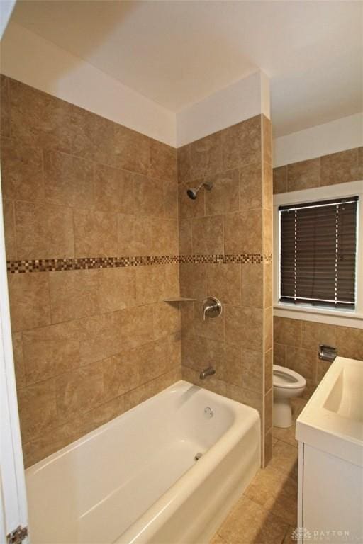 full bath with bathtub / shower combination, toilet, vanity, tile walls, and tile patterned floors