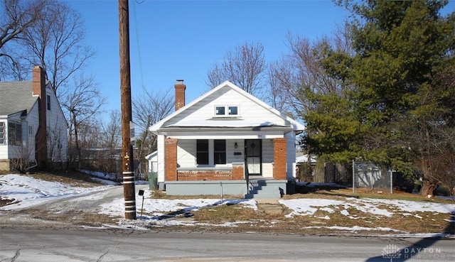 view of front facade with a porch, an outbuilding, and a chimney