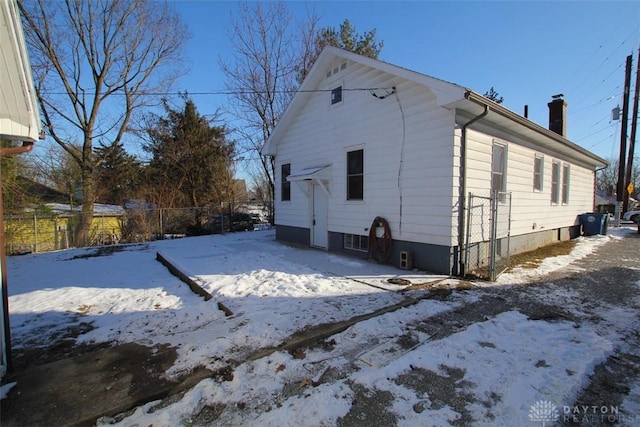 snow covered property featuring a chimney and fence