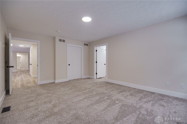 unfurnished bedroom featuring a textured ceiling and light carpet