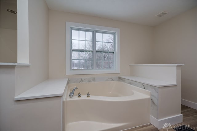 bathroom with a bath and hardwood / wood-style floors