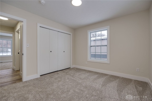 unfurnished bedroom with multiple windows, a closet, and light carpet