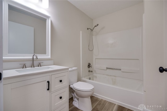 full bathroom featuring hardwood / wood-style flooring, washtub / shower combination, vanity, and toilet