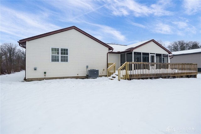 snow covered back of property featuring a deck, cooling unit, and a sunroom