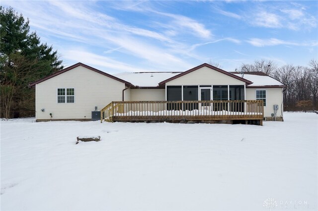 snow covered property with a deck, a sunroom, and central AC unit