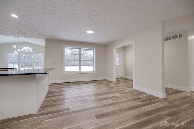 unfurnished living room with a textured ceiling, a chandelier, and plenty of natural light