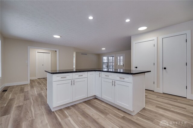 kitchen with a center island, a textured ceiling, light hardwood / wood-style floors, and white cabinetry