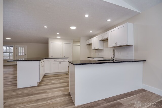 kitchen featuring sink, light hardwood / wood-style flooring, white cabinetry, and kitchen peninsula