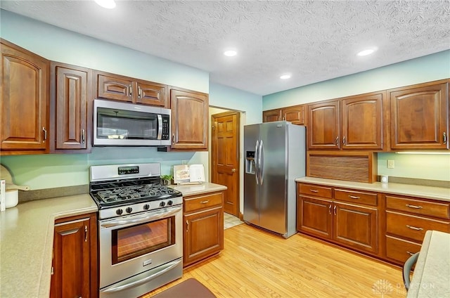 kitchen featuring a textured ceiling, stainless steel appliances, and light wood-type flooring