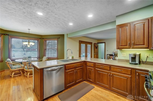 kitchen featuring an inviting chandelier, sink, hanging light fixtures, kitchen peninsula, and stainless steel dishwasher