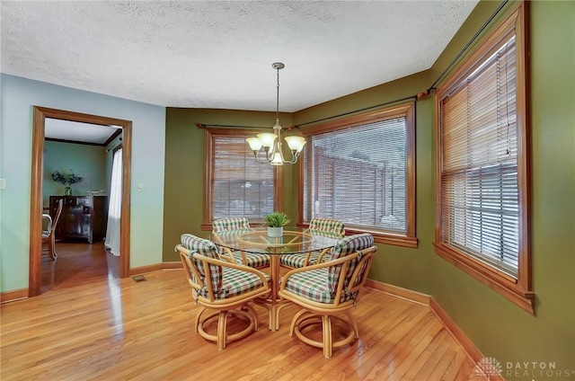 dining area featuring light hardwood / wood-style floors, a textured ceiling, and a chandelier