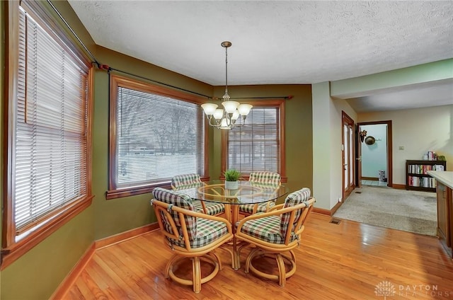 dining space featuring a textured ceiling, an inviting chandelier, and light hardwood / wood-style floors