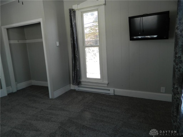 unfurnished bedroom featuring a closet, dark carpet, and a baseboard heating unit