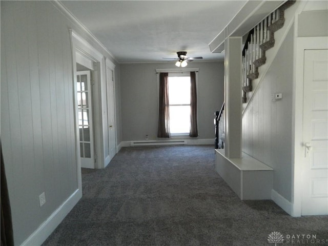 carpeted spare room featuring ornamental molding, ceiling fan, wood walls, and baseboard heating