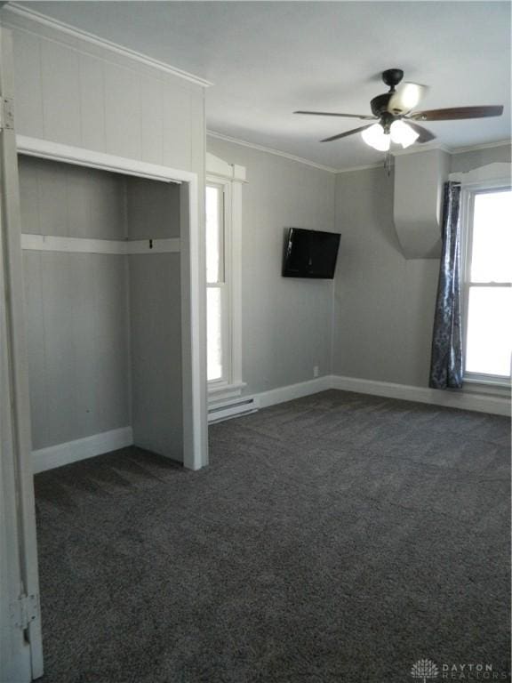 unfurnished bedroom with dark carpet, ornamental molding, and ceiling fan