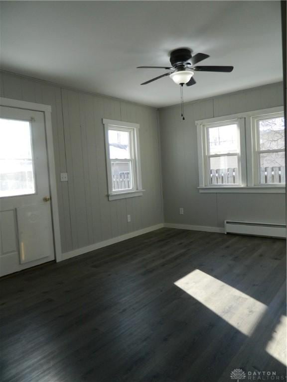 interior space with baseboard heating, ceiling fan, a healthy amount of sunlight, and dark hardwood / wood-style floors