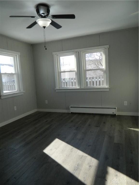 unfurnished room featuring dark hardwood / wood-style flooring, baseboard heating, and ceiling fan