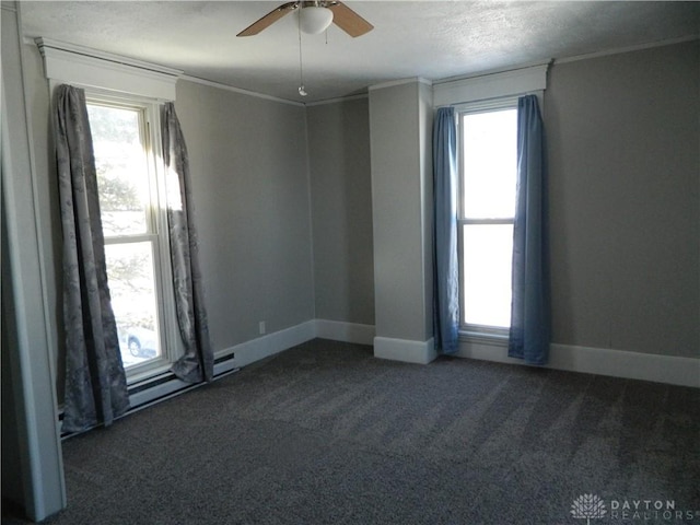 empty room featuring a healthy amount of sunlight, ceiling fan, crown molding, and dark carpet