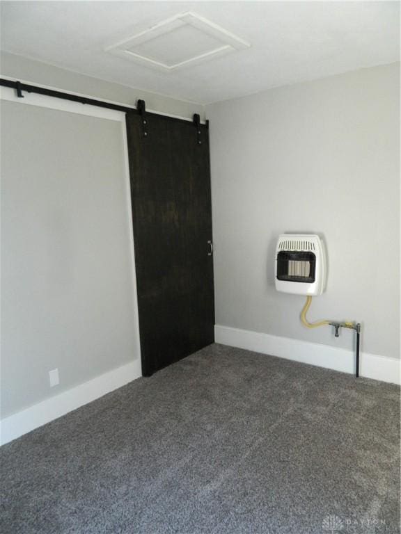 empty room featuring heating unit, a barn door, and dark carpet