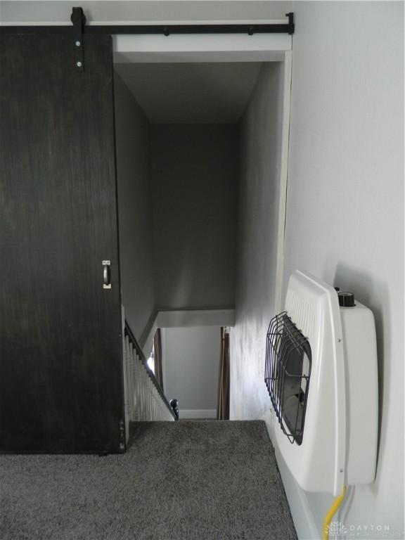 stairs with a barn door and carpet