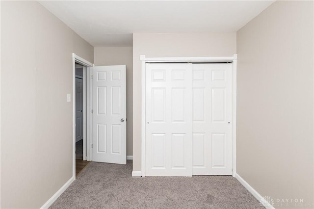 unfurnished bedroom with light colored carpet and a closet