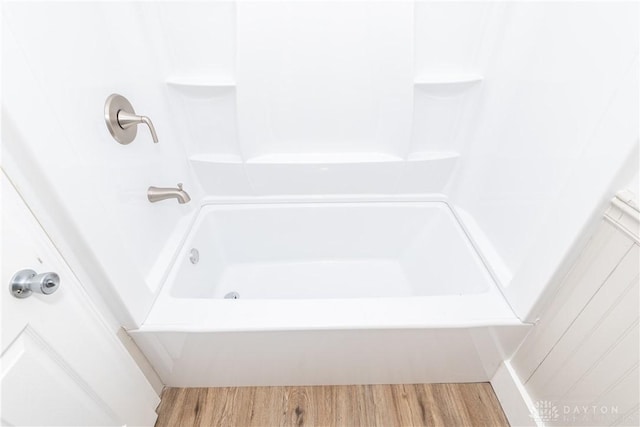 bathroom with hardwood / wood-style floors and bathing tub / shower combination