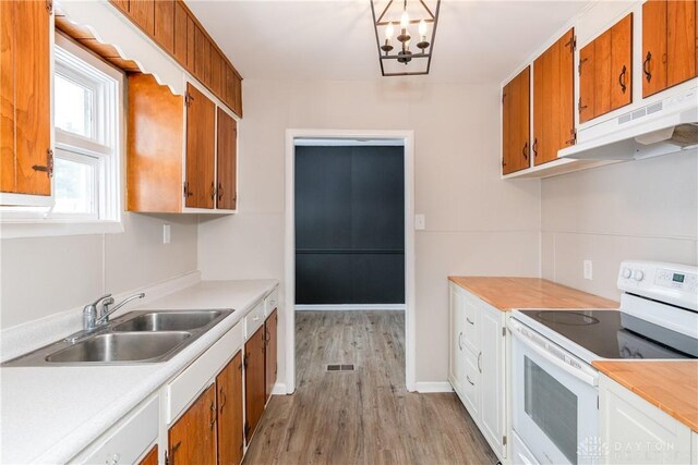 kitchen with sink, light hardwood / wood-style flooring, white electric range, and an inviting chandelier