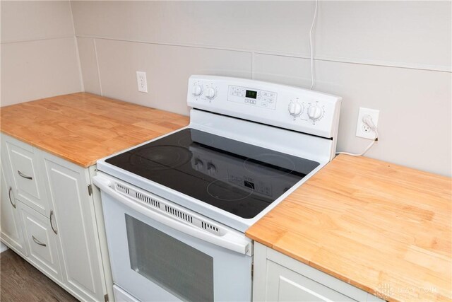 kitchen featuring dark wood-type flooring, white electric stove, and white cabinetry