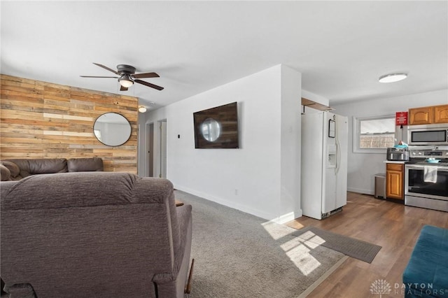 living room with dark wood-type flooring, ceiling fan, and wood walls