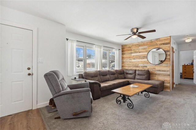 living room with ceiling fan and wood walls