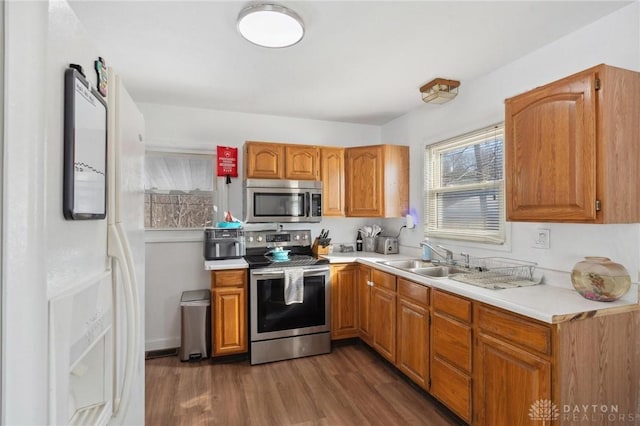 kitchen with appliances with stainless steel finishes, sink, and dark wood-type flooring