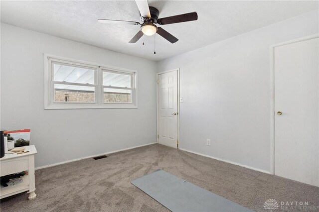 empty room with ceiling fan and carpet flooring