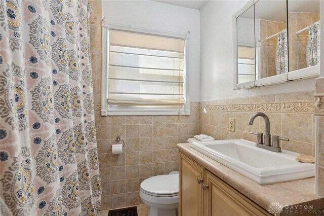 bathroom featuring toilet, vanity, tile walls, and curtained shower