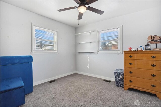 living area with ceiling fan, a wealth of natural light, and light carpet