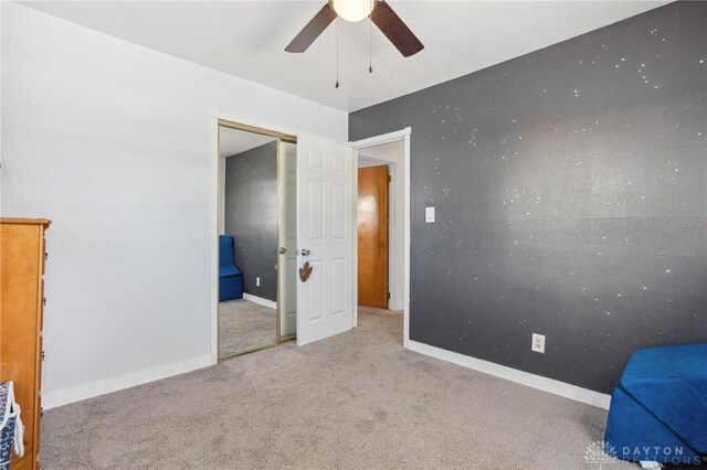 unfurnished bedroom with ceiling fan, a closet, and light carpet