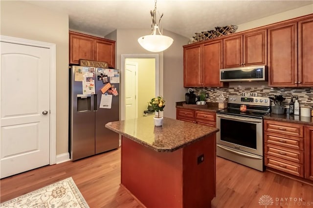 kitchen with appliances with stainless steel finishes, light hardwood / wood-style floors, hanging light fixtures, and a center island