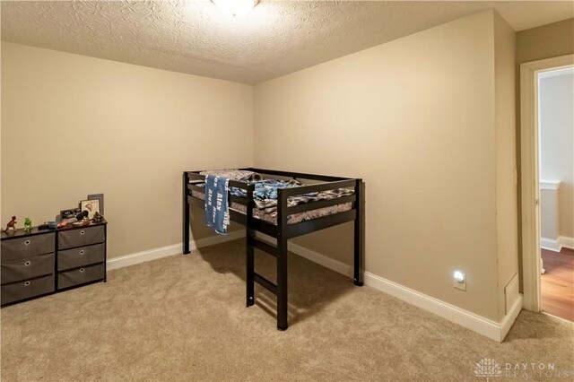 bedroom with light colored carpet and a textured ceiling