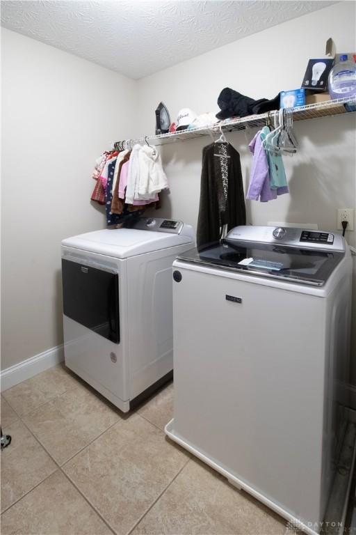 clothes washing area with light tile patterned floors, a textured ceiling, and separate washer and dryer