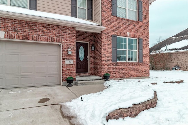 snow covered property entrance with a garage