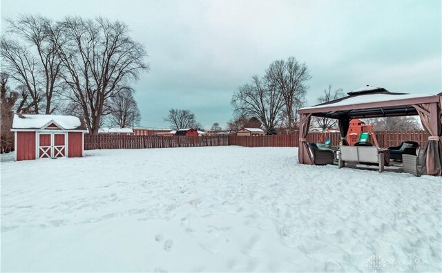 yard covered in snow with a gazebo and a shed