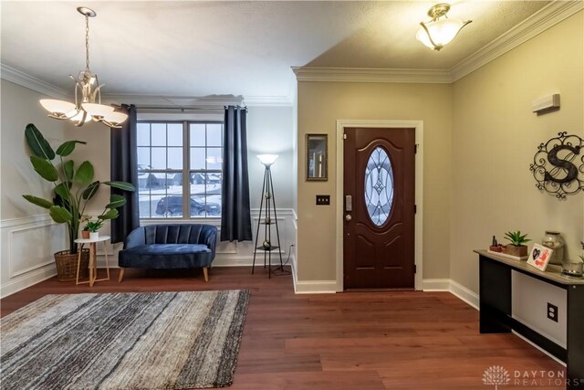 entryway with a notable chandelier, dark wood-type flooring, and crown molding