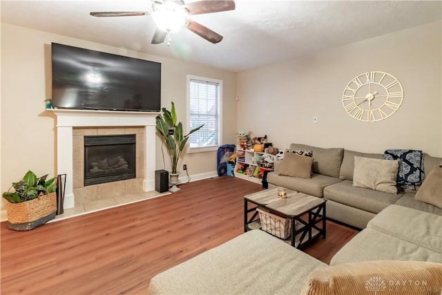 living room with a tiled fireplace, hardwood / wood-style floors, and ceiling fan