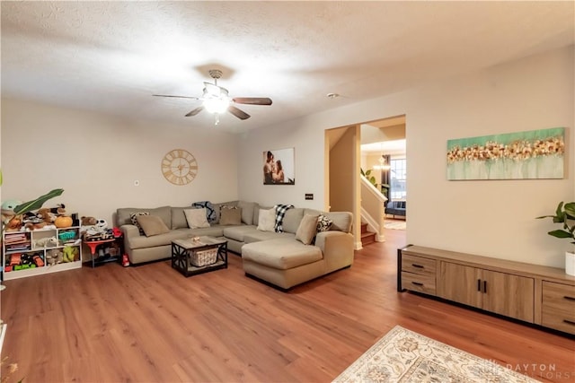 living room featuring a textured ceiling, ceiling fan, and light hardwood / wood-style flooring