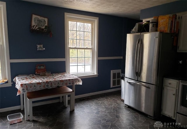 kitchen featuring a textured ceiling and stainless steel fridge