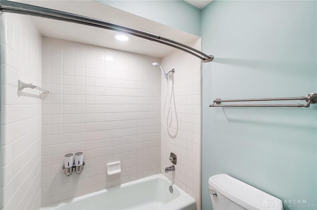 bathroom with tiled shower / bath combo and toilet