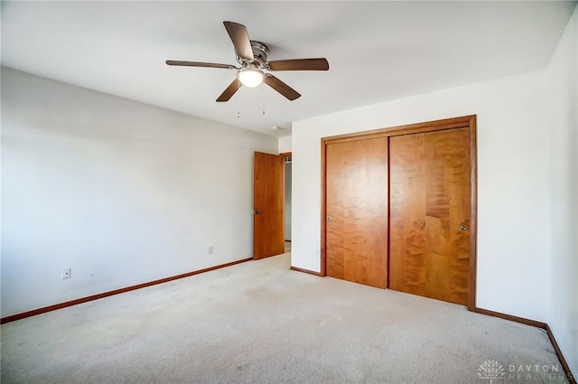 unfurnished bedroom featuring ceiling fan, a closet, and light carpet