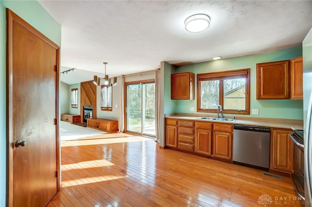 kitchen featuring an inviting chandelier, light hardwood / wood-style floors, decorative light fixtures, dishwasher, and sink